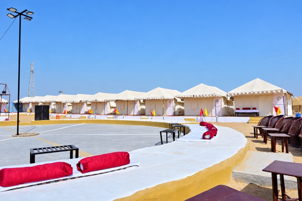 Daytime view of RETIVAA DESERT CAMP luxury desert camp featuring circular amphitheater, lush lawn, and rows of pristine swiss tents