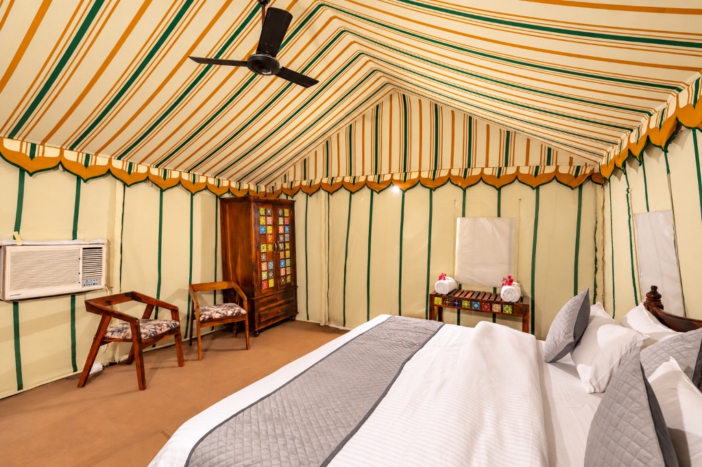 Luxury royal tent suite with plush king bed, striped canopy, and handcrafted furniture